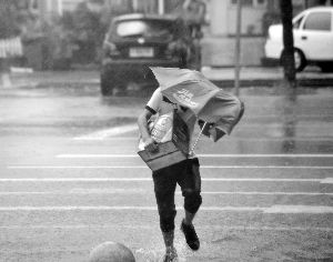 三亚街头的一位行人冒雨过街。