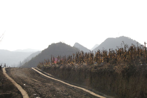 家外的小路通向村子，更远处是一层又一层的大山。