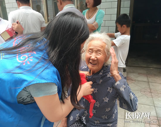 志愿者为老妈妈戴上大红花。