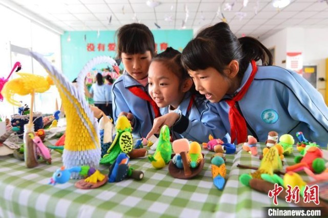 学生讨论手工制作的太空泥小鸟。　王海滨 摄